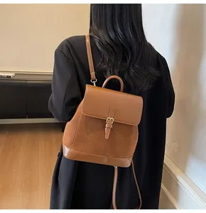 Detail view of a vintage brown suede backpack with faux leather trim on a model