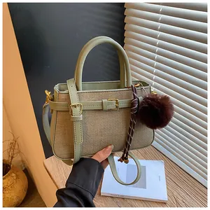 Detail of light green woven bucket bag featuring gold hardware and a brown plush charm