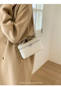 Lifestyle shot of white rectangular leather box bag with silver zippers and thin strap