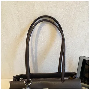 Close-up of brown faux leather tote bag with silver zipper and ring hardware detail