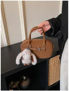 Detailed shot of a brown vintage leather square handbag with a plush bunny charm