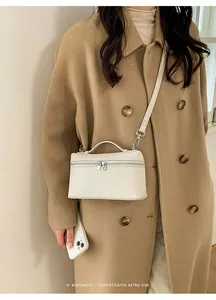 Close-up of a cream white leather crossbody box bag with a camel wool coat outfit