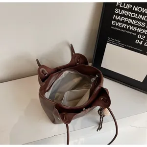 Top view of large brown leather tote bag interior with zipper and plush ball charm