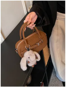 Detailed close-up of brown leather handbag with silver hardware and a rabbit plush charm