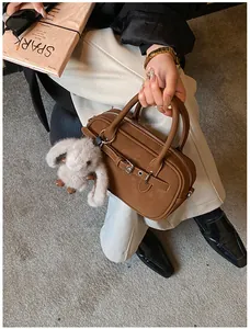 Detail of brown leather boston bag with silver hardware and grey plush rabbit charm