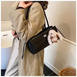 Detail of black quilted shoulder bag with silver turn-lock and cute bunny charm