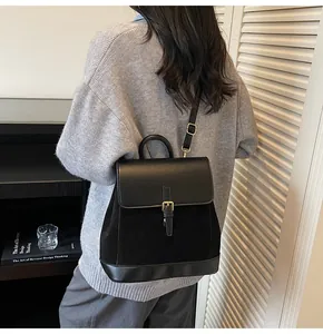 Detail showing the mixed leather textures and golden hardware on the black backpack