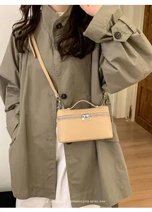 Close-up of minimalist beige box bag with silver zipper and detachable shoulder strap