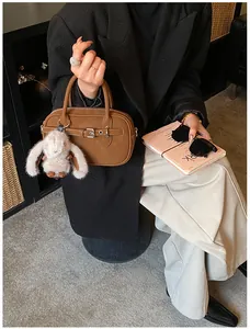 Detail view of a vintage brown leather Boston bag with a cute white bunny plush keychain