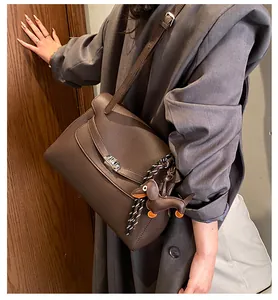 Detail of dark brown lychee grain leather crossbody bag with silver rotating lock