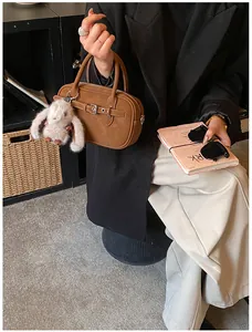 Brown vintage handbag with metal buckle and plush rabbit charm in a lifestyle setting