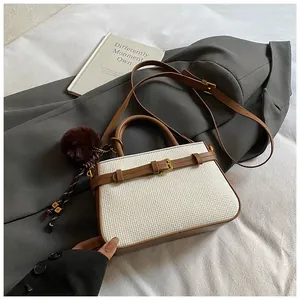 Detail view of woven beige fabric and brown leather bucket bag with plush ball charm