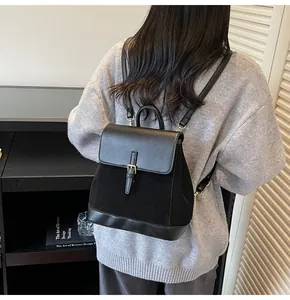 Detail view of black faux suede and leather backpack featuring buckle strap and flap closure