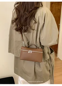 Brown retro leather handbag with silver lock shown worn by model in minimalist setting