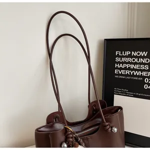 Detail of dark brown tote bag showing smooth matte texture and silver metal ball accents