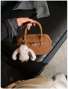 Detail of vintage brown textured leather handbag with a white plush bunny charm