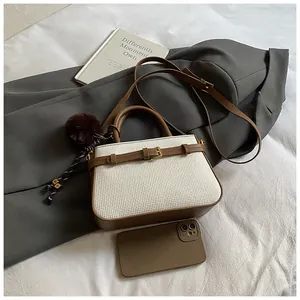 Detail view of small retro bucket bag with tweed texture, brown trim and plush charm
