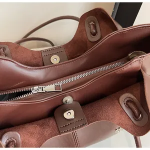 Detail of dark brown tote bag internal compartments with silver zipper and magnetic buckles