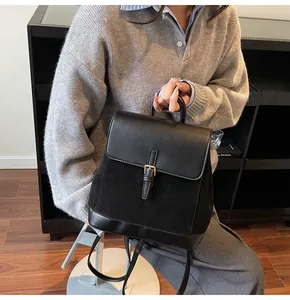 Detail of a chic black leather and suede拼接 backpack featuring a metallic buckle closure