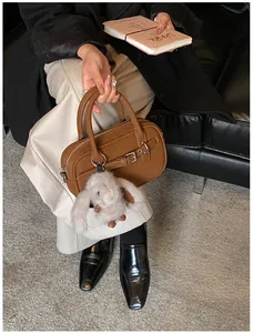 Brown leather handbag detail featuring a plush bunny charm and polished metal buckle