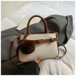 Detail of white checkered mini bucket bag with brown leather trim and plush pompom charm