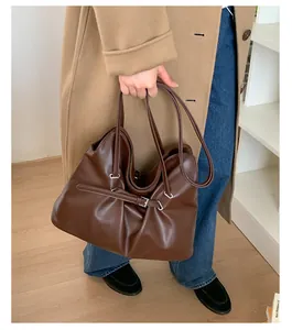 Detail of dark brown tote bag featuring adjustable buckle straps and silver-toned hardware
