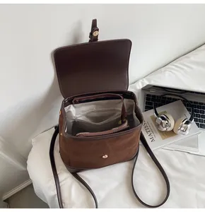 Overhead view of coffee brown faux suede backpack interior with zipper pocket and accessories