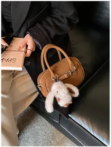 Detail view of a vintage brown leather handbag featuring a white plush rabbit pendant decoration