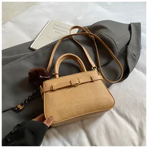 Detail of woven texture khaki bucket bag with plush charm and golden metal buckle