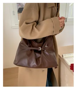 Close-up of vintage brown leather tote bag with silver buckle on a stylish wool coat