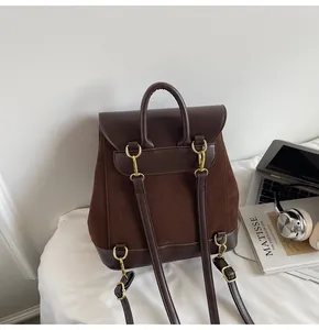 Close-up of retro dark brown suede backpack with leather straps on a white bed