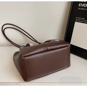 Detail view of large brown leather tote bag with silver beads and wide stable base
