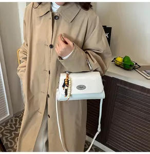 Detail der weißen Handtasche aus Leder mit Metall-Drehverschluss und Perlenanhänger