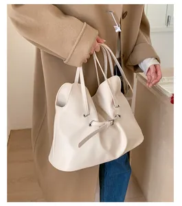 Detailed side view of cream pleated tote bag with metal eyelets and double shoulder straps