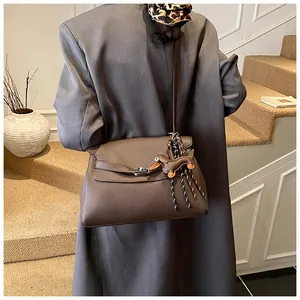 Detail of vintage brown textured leather satchel with a cute dachshund bag charm