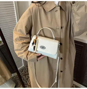 Detailansicht der cremefarbenen PU-Handtasche mit silbernem Drehverschluss und Perlen