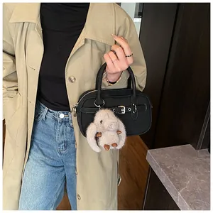 Detail of a vintage black handbag with a decorative buckle and a plush rabbit charm