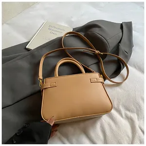 Detailed view of light brown bucket bag with gold hardware on a grey blazer