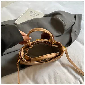 Top view of khaki bucket bag with gold hardware, plush red charm and interior zipper details