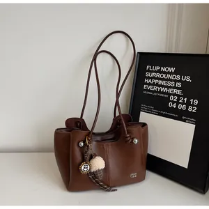 Detailed close-up of dark brown matte leather tote bag with silver ball trim and fur charm