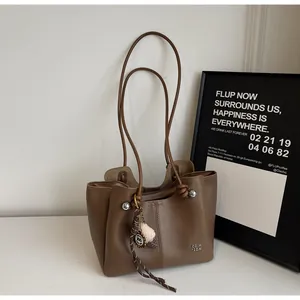 Close-up of dark brown tote bag with silver beads and woven pendant decoration
