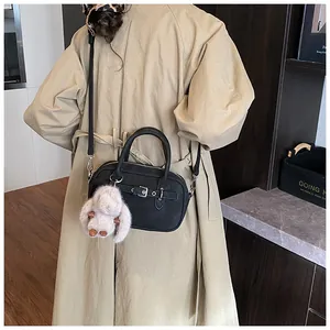 Detail of vintage black leather handbag with silver buckle and plush rabbit charm