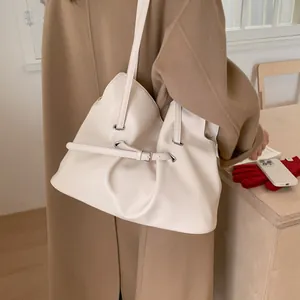 Minimalist beige PU leather tote bag with decorative buckle and wide strap on shoulder
