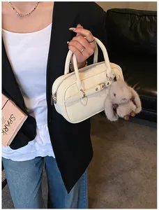 Close-up of cream textured leather handbag featuring a cute plush bunny charm detail