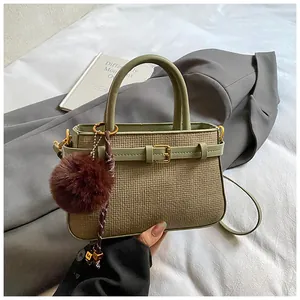 Detailed close-up of olive green bucket bag with straw texture and leather trim