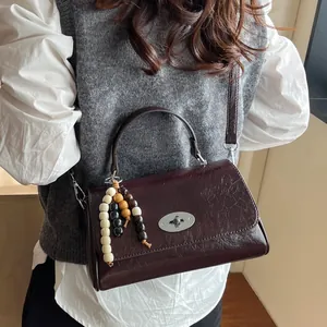 Dunkelrote Leder-Henkeltasche mit Vintage-Textur und modischem Holzperlen-Anhänger