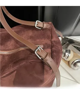 Macro shot of adjustable leather straps and smooth zipper on a vintage suede tote bag