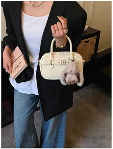 Detail of beige square crossbody bag with silver buckle and plush rabbit keychain