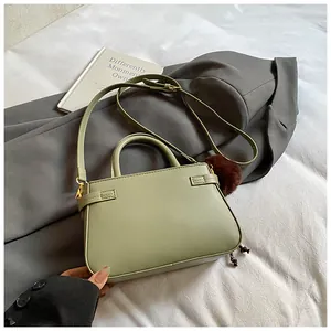 Detail of light green bucket bag with adjustable strap and decorative fur pompom