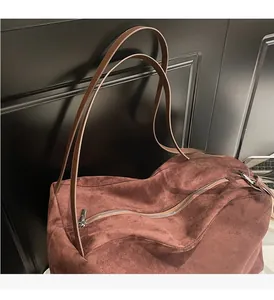 Detail of red-brown suede tote bag featuring slim leather handles and silver zipper
